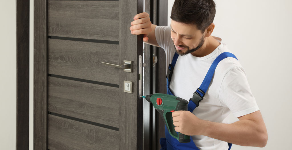 Artisan menuisier installant une porte d'entrée en bois haute performance thermique sur chantier